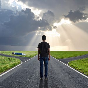 Photorealistic scene showing a young person standing at a crossroads in a dramatic landscape